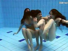 Three girls in bikinis swim and strip in pool
