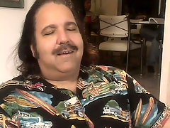 Ron Jeremy has a gorgeous babe blowing his big prick by the fireplace