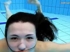 Beautiful girl swims and smiles underwater